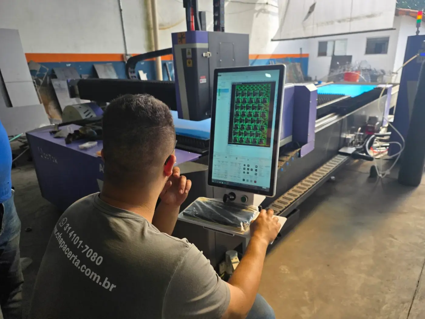 Operador acompanhando o corte no painel da máquina laser